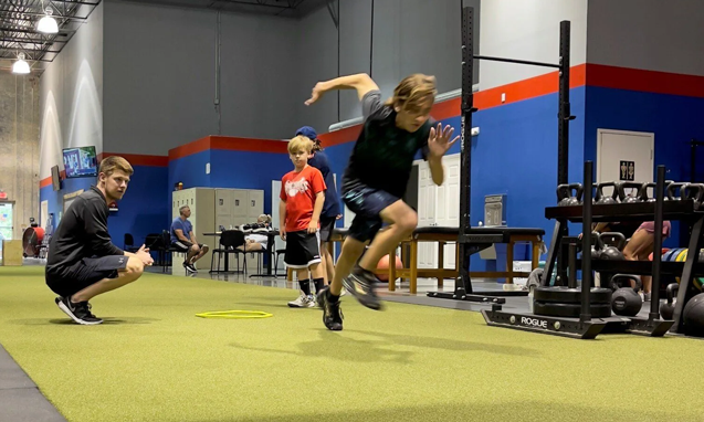 Youth athlete sprinting during speed and agility training with coach at Freedom Fitness gym in St. Peters, Missouri