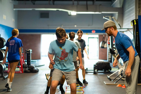 Youth athletes doing ladder agility drills with coach at Freedom Fitness gym in St. Peters, Missouri