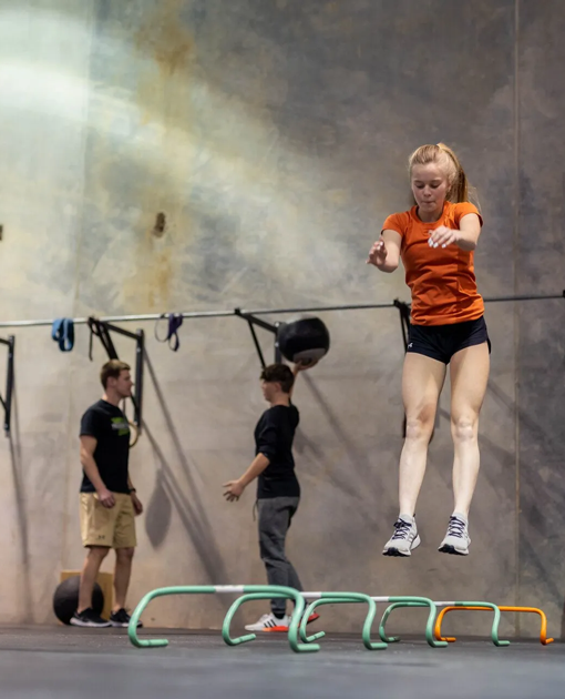 Young athlete jumping over agility hurdles during training at Freedom Fitness gym in St. Peters, Missouri